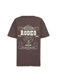 T-shirt in cotone marrone con testo stampato bianco e motivi decorativi. Il design include "RODEO", "WILD WEST", "HOUSTON" e "1991".