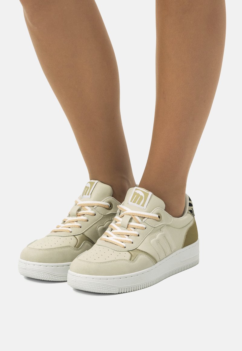 Sneaker in pelle beige con punta perforata, lacci crema e suola bianca. Tallone in verde oliva con dettagli del logo sulla linguetta.