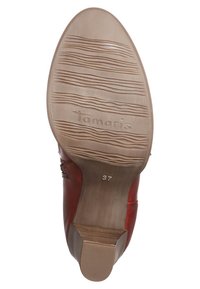 Semelle de chaussure en caoutchouc marron avec des rainures texturées et des inscriptions. Comprend le nom de la marque "Tamaris" et la taille "37" embossés.