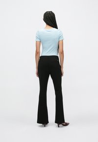 Ελαφρύ μπλε κοντομάνικο τοπ σε συνδυασμό με μαύρο παντελόνι καμπάνα. Το τοπ έχει στρογγυλή λαιμόκοψη και το παντελόνι διαθέτει πίσω τσέπη. Ομαλή υφή σε όλο το ύφασμα.