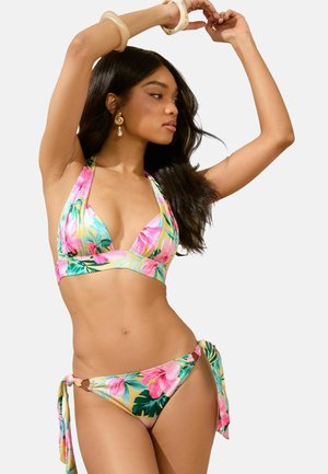 Gėlių bikini komplektas su viršumi su kaklo raišteliu ir žemai kylantiomis kelnaitėmis. Su rožinėmis ir žalios tropinėmis raštinėmis ant minkštos medžiagos. Raišteliai šoniniuose siūluose.