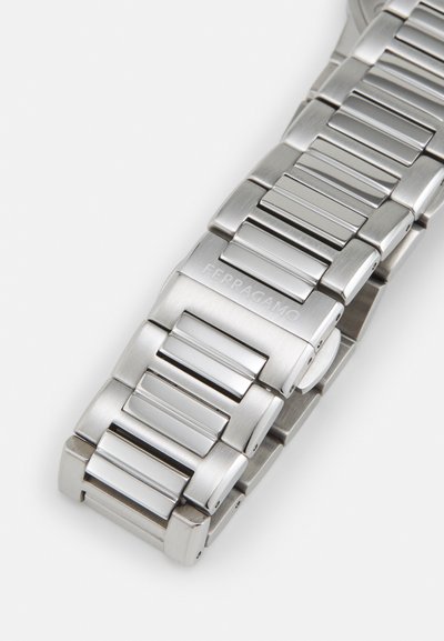 Silver stainless steel watch bracelet with rectangular links and polished accents. Features engraved "Ferragamo" logo on one link.