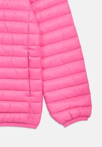 Φωτεινό ροζ μπουφάν με επένδυση σε ύφασμα καπιτονέ, με ελαστικό μανσέτα και ορατή πλαϊνή τσέπη με φερμουάρ, που δείχνει τις οριζόντιες ραφές με επένδυση.