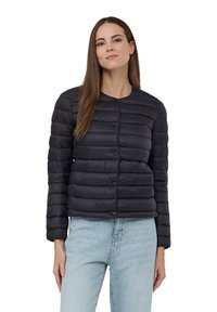 Giubbotto in piuma nero con design corto, texture a righe orizzontali, scollatura rotonda e chiusura con bottoni. Indossato con jeans azzurri chiari.