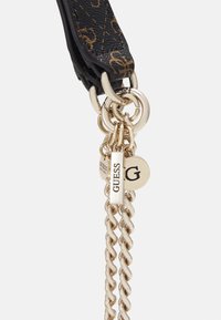 Zwarte textuurriem met hardware in goudkleur. Heeft gegraveerde ronde en rechthoekige logotags die aan de schakels van de ketting zijn bevestigd.