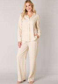 Beige linnen shirt en wijde broek set, met een knoopsluiting, borstop zak en relaxte pasvorm; gladde textuur, minimale details.