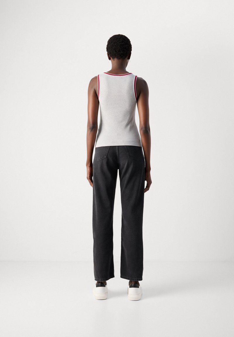 Graues Tanktop mit rotem Rand, kombiniert mit schwarzen weiten Jeans und weißen Sneakers. Glatte Textur, figurbetonter Schnitt und lässiger Stil.