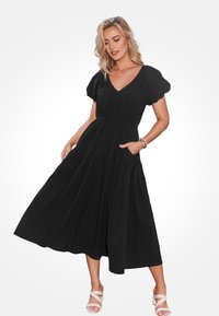 Czarna midi sukienka z bufiastymi rękawami, dekoltem w serek, marszczeniami i kieszeniami; wykonana z lekkiego materiału o zwiewnym kroju.