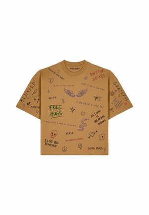 Braunes T-Shirt mit verschiedenen handschriftlichen Sprüchen und kleinen Zeichnungen, darunter Flügel, eine Schlange, ein Herz, ein Friedenzeichen, ein Totenkopf und ein Dollarzeichen.