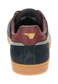 Sneaker in suede blu navy con tacco in pelle bordeaux e accentuazione del logo dorato. Presenta una pannello laterale beige e una suola in gomma color caramello.
