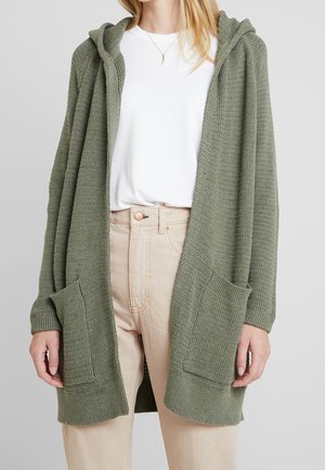 Oliwkowy sweter robiony na drutach z kapturem, otwarty z przodu, z dwiema przednimi kieszeniami. Posiada ściągacze przy mankietach i dolnej krawędzi, oraz fakturowany materiał.