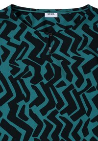 Teal bluse med abstrakte sorte zigzag-mønstre, rund halsudskæring med en knapdetalje og en glat, let stofstruktur.