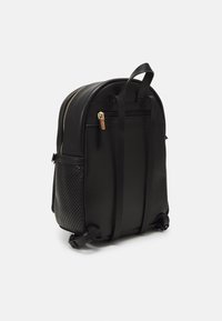 Svart ryggsäck i slätt syntetiskt material, med guldzipper och en texturerad meshnedficka. Minimalistisk design med justerbara remmar.