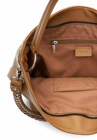 Polygonowa skórzana torebka o miękkiej fakturze, z dwoma uchwytami, kieszenią na zamek i materiałową podszewką w jaśniejszym odcieniu brązu.