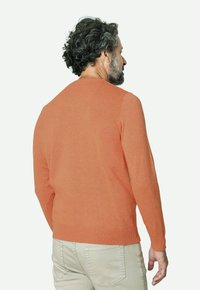 Suéter de cuello redondo y manga larga en naranja, hecho de una tela suave. Presenta puños y dobladillo acanalados, con una textura lisa y sin patrones visibles.