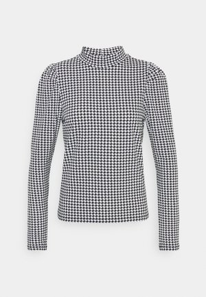 Zwart-wit geruit houndstooth patroon langermige coltrui met licht opgepofte schouders op een effen achtergrond.