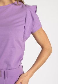 Korte mouwen lila shirt met een minimalistisch ontwerp, voorzien van subtiele schouderplooien en een zachte, gladde textuur.