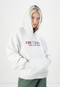 Gray hoodie made of cotton blend with a kangaroo pocket and drawstring. Features "Carhartt Work In Progress" logo in purple across the chest.