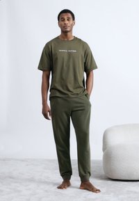 Λαδί βαμβακερό t-shirt με το λογότυπο "TOMMY HILFIGER", σετ με αντίστοιχο παντελόνι jogger λαδί. Απαλή, άνετη εφαρμογή. Απλή υφή.