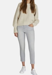 Suéter de punto crema con cuello redondo y textura de canalé; combinado con pantalones cortos de rayas grises y zapatillas blancas.