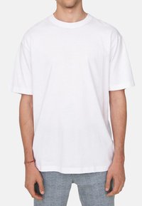 Weißes Baumwoll-T-Shirt mit rundem Halsausschnitt, kurzen Ärmeln und lockerer Passform, das eine glatte Textur aufweist und keine sichtbaren Grafiken oder Muster hat.