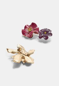 To blomsterhårnåle: den ene i mørk pink emalje med gulddetaljer, den anden i dyb lilla emalje med struktureret guldhardware på bagsiden.