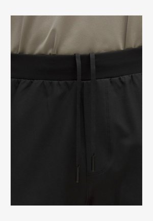 Pantalones cortos negros con una cintura elástica ancha que cuenta con cordones, tela suave y detalles de costuras sutiles.