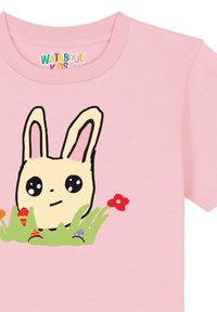 Roze katoenen T-shirt met een cartoonkonijn met grote ogen, omringd door groene gras en kleurrijke bloemen, wat het speelse ontwerp versterkt.