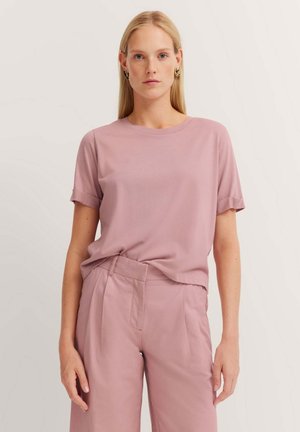 Helles rosa Kurzarm-T-Shirt mit Rundhalsausschnitt und umgeschlagenen Ärmeln, aus weichem Stoff; kombiniert mit passender hochtaillierter Hose.