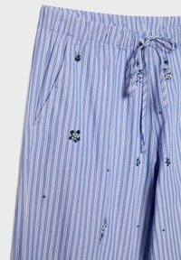 Pantalon rayé bleu et blanc avec taille élastique, cordon de serrage, poches latérales et petits détails brodés de perles florales.