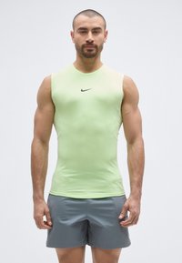 Light green sleeveless athletic shirt with a rounded neckline, fitted design, and black Nike logo on the chest; paired with gray shorts.