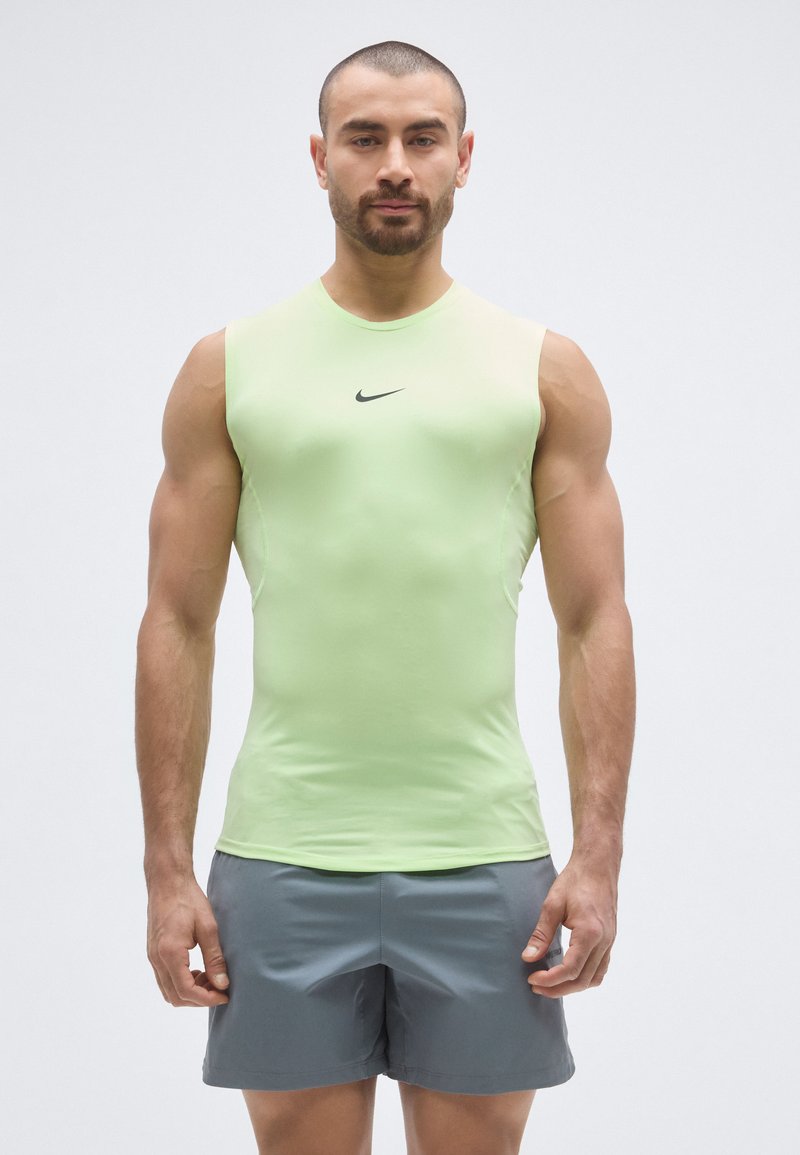 Light green sleeveless athletic shirt with a rounded neckline, fitted design, and black Nike logo on the chest; paired with gray shorts.