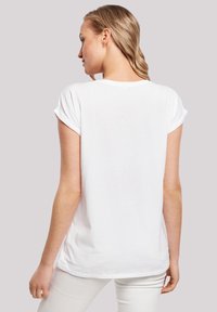 White, short-sleeved T-shirt made of soft cotton. Features a relaxed fit with rolled sleeves and a curved hem at the back.