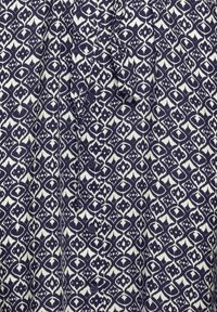 Tamsiai mėlynas ir baltas geometrinis raštas audinys su mygtukais ir surištos audinio diržo detalėmis.