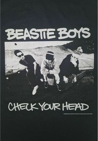 Camiseta de algodón negra con un gran gráfico blanco de tres individuos sentados. El texto "BEASTIE BOYS CHECK YOUR HEAD" se muestra de manera prominente.