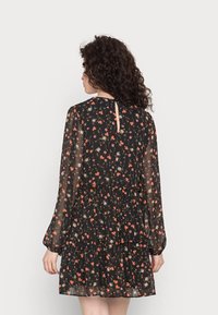 Vestido preto floral com mangas longas e transparentes, saia em camadas e detalhe nas costas em forma de buraco, realçado com padrões de flores laranja e rosa.