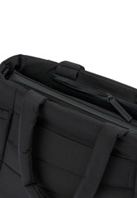 Musta pehmustettu laukku, jossa on kaksinkertaiset kahvat, varustettu vetoketjullisella lokeroilla ja sileällä sisävuorella. Minimalistinen muotoilu, jossa on hienovaraisia saumaelementtejä.