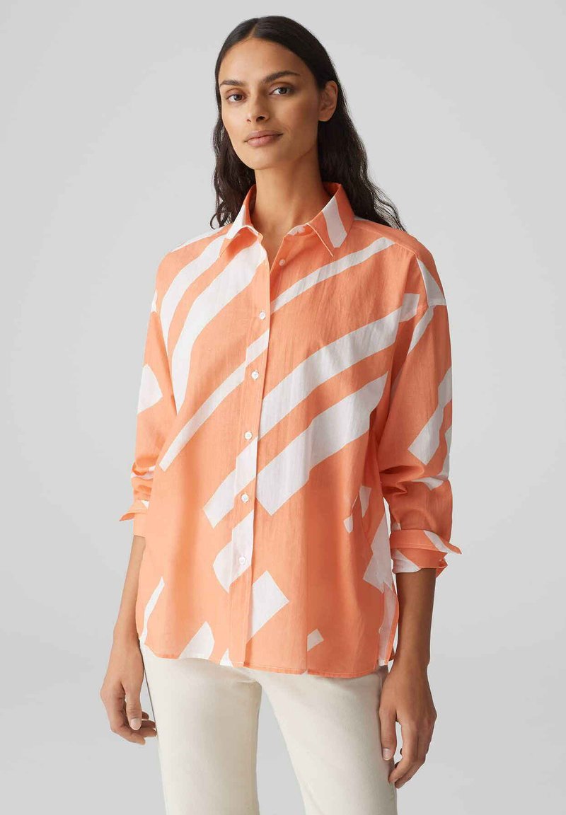 Camicia button-up arancione e bianca con un motivo a righe diagonali, realizzata in tessuto leggero, dotata di maniche lunghe e vestibilità rilassata.