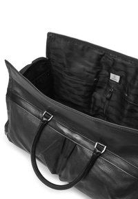 Svart läder duffelväska med texturerad yta, dragkedjestängning, dubbla handtag och mönstrad svart foder med ytterligare fickor inuti.