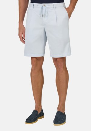 Lyseblå bomulds shorts med folder, forlommer, snor i taljen og opretstående kanter, parret med mørkeblå ruskinds slip-on sko.