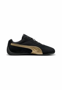 Scarpa sportiva nera con tomaia texturizzata, dettagli dorati sui lati e suola in gomma. Presenta lacci e un design elegante.