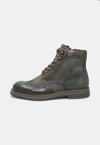 Stivali alla caviglia in pelle marrone scuro con dettagli brogue, chiusura con lacci e suola piatta in gomma. Materiali lisci e testurizzati si combinano nel design.