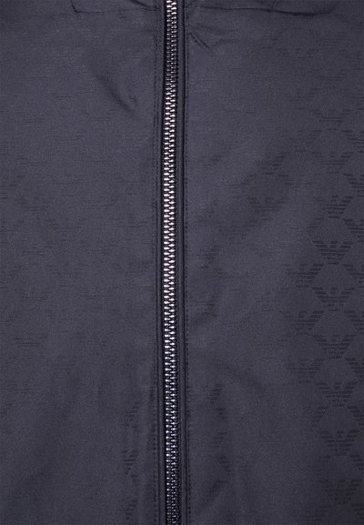 Black zip-up jacket featuring a smooth fabric with a subtle embossed pattern, center zipper, and a sleek texture.