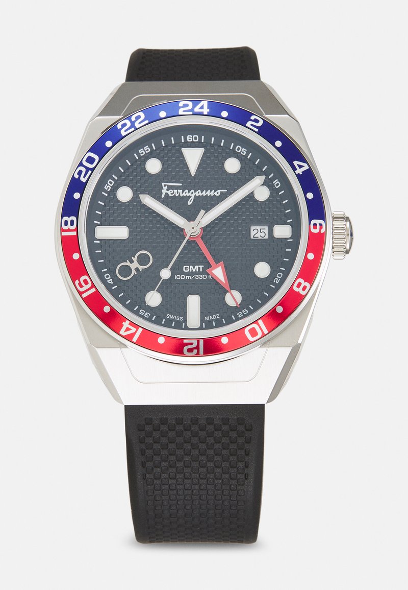 Ferragamo pulkstenis ar melnu gumijas siksnu, sudraba korpusu un teksturētu pelēku ciparnīcu. Ieqlauj sarkanu un zilu rāmīti, gaismas stundas marķierus un datuma logu.