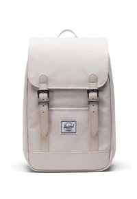 Ljusbeige ryggsäck med lock, två framspännen och en logotypapplikation. Tillverkad av slitstarkt tyg, med rektangulär form och slät textur.