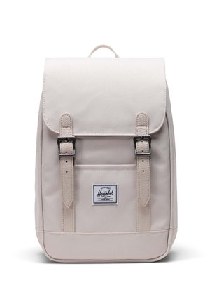 Helles beiges Rucksack mit Klappe, zwei vorderen Schnallen und einem Logopatch. Hergestellt aus strapazierfähigem Stoff, hat eine rechteckige Form und eine glatte Textur.