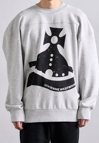 Grå oversized sweatshirt i bomull med en svart grafisk design och texten "Vivienne Westwood" på framsidan. Enkel rund halsringning.