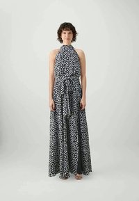 Vestido longo em preto e branco com padrão de bolinhas, design de alças, detalhe de faixa na cintura e comprimento até ao chão, apresentando uma textura de tecido suave.
