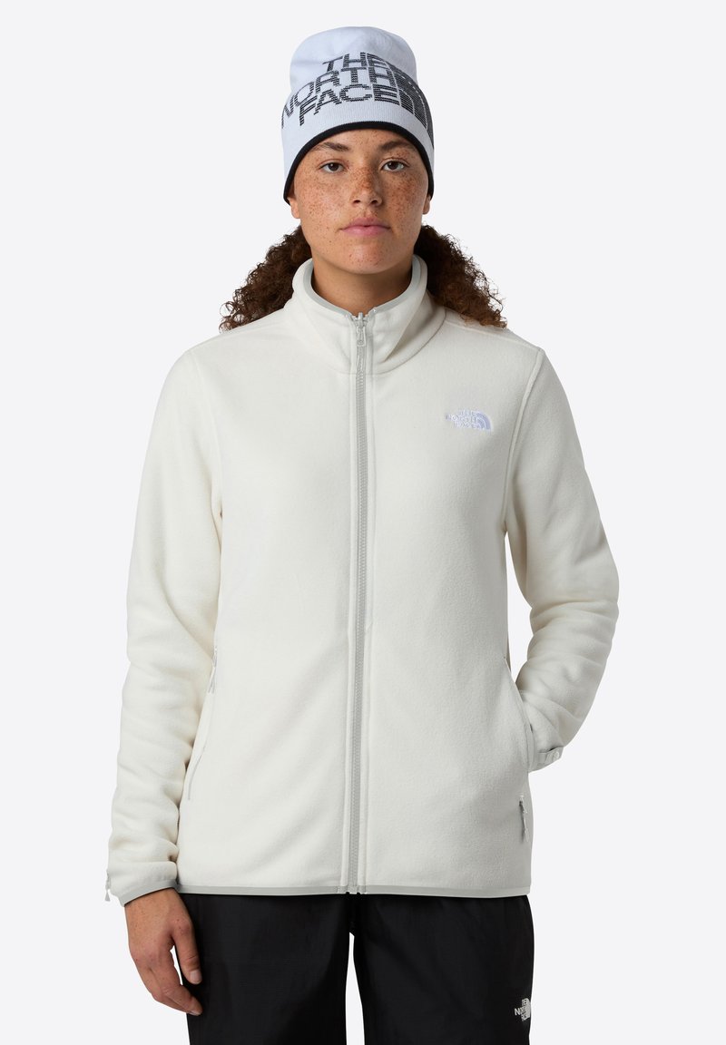 Jachetă albă din fleece cu guler înalt, fermoar frontal și buzunare laterale; are un mic logo reflectorizant pe pieptul stâng.