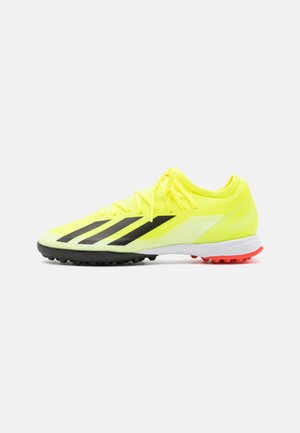 Scarpino da calcio giallo brillante con strisce nere, tomaia sintetica leggera, design a profilo basso, suola in gomma con accenti rossi.